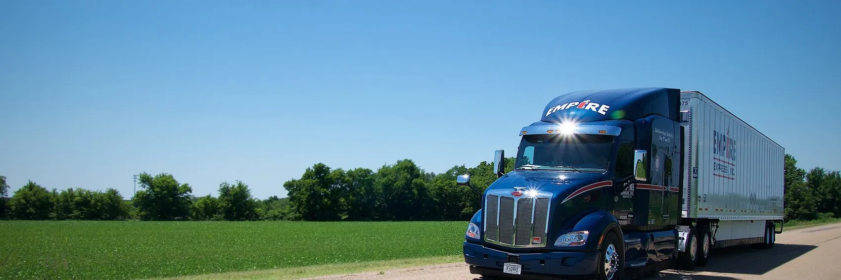 An Empire Express tractor-trailer running a rural two-lane road past green fields